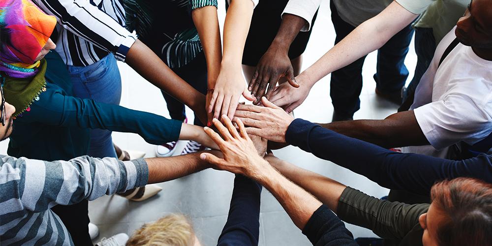 A diverse team joining hands in preparation for a shared project
