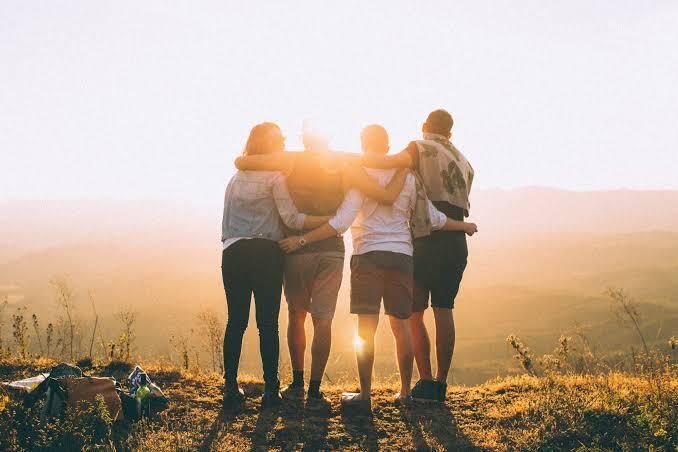 Friends holding hands together while looking toward the sunset