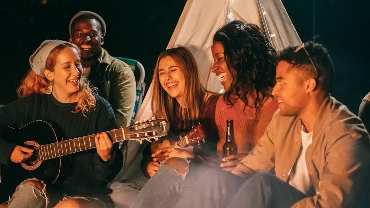 A diverse group of friends chatting, laughing, and playing music together